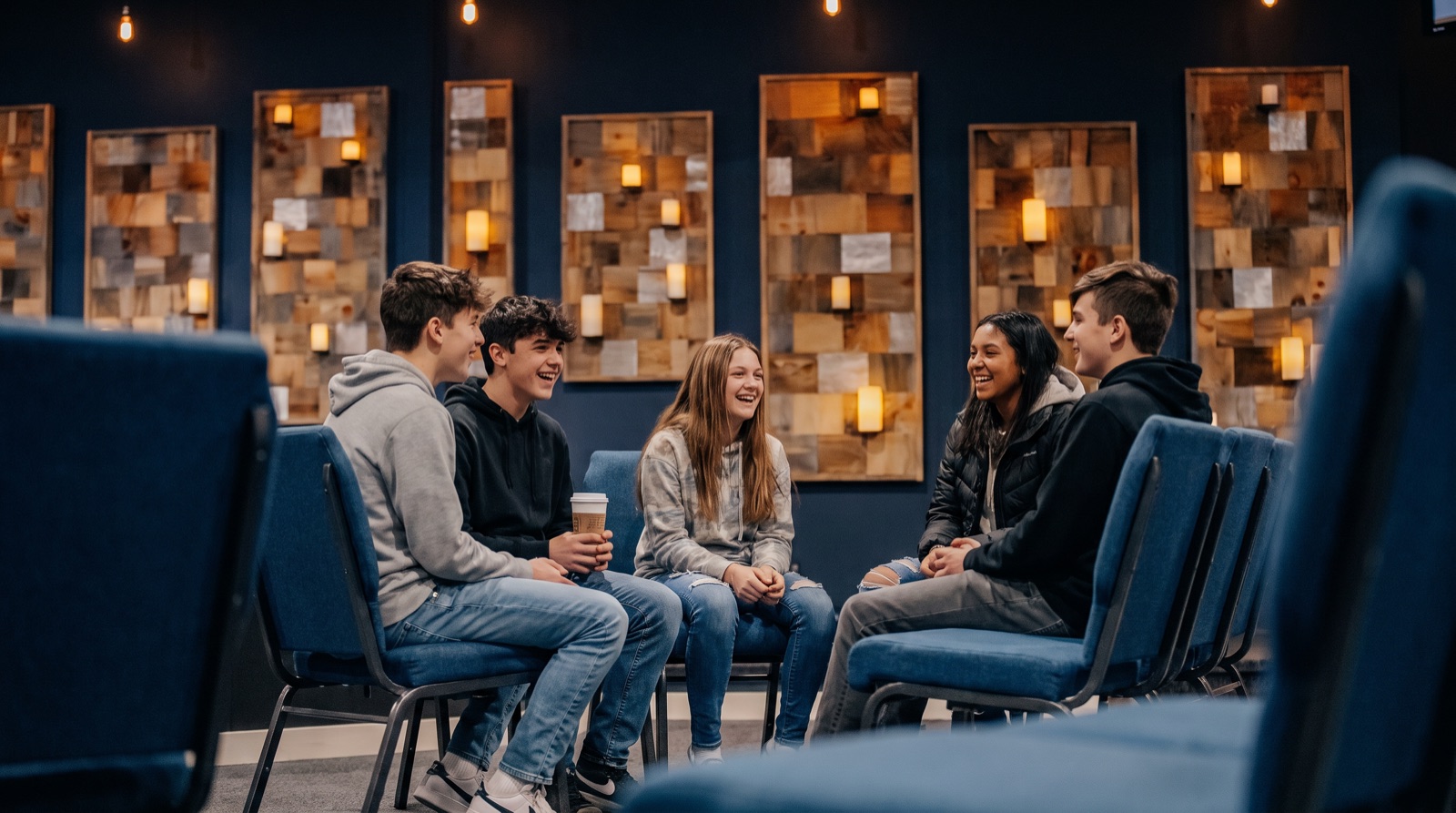 Teenagers laughing together in a circle of chairs